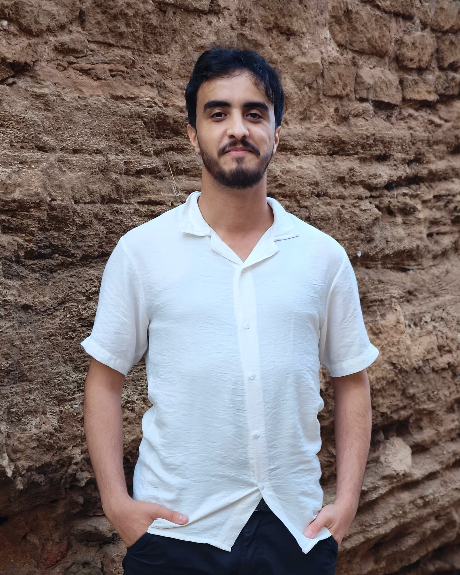 Ayoub Elakhdar standing in front of a stone wall